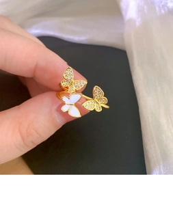Detail of three-butterfly adjustable gold ring with white enamel and zircon accents