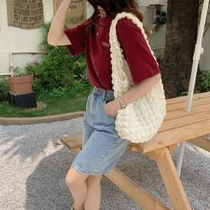 Outdoor lifestyle shot of a cream bubble texture tote bag with a chic casual outfit