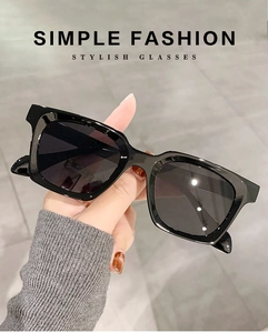 Close-up of a black square frame sunglasses showing precise metal hinge and finish
