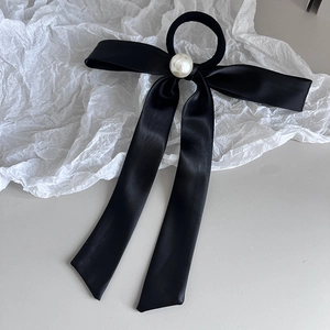 Elegant black ribbon bow hair tie with large pearl accent on minimalist background
