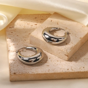 Detail of silver drop-shaped earrings with mirror polish finish on stone surface