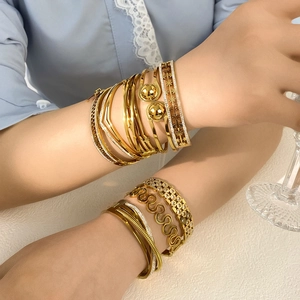 Elegant gold stacked bracelets with geometric lines and floral patterns on female wrist