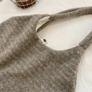 Detail of grey tweed tote bag featuring colorful flecks and a magnetic snap button