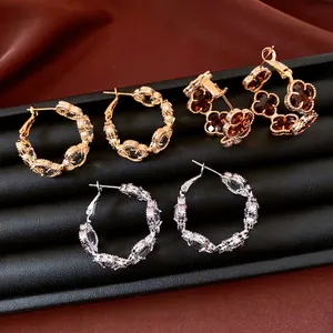 Élégantes boucles d'oreilles fleur et trèfle plaquées or 18k avec zircons en vitrine