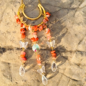 Detail of handmade moon suncatcher with orange crystals and transparent butterfly beads