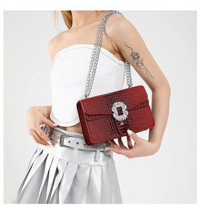 Detail of burgundy crocodile-textured bag with large crystal buckle and silver chain