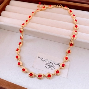 Macro detail of vintage gold chain with oval red gemstones and textured metal finish