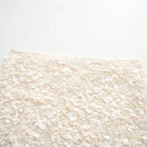 Detailed macro shot of shimmering cream-colored sequins on elegant mini skirt fabric