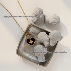 Macro detail of bee heart lock necklace with gold-plated chain on vintage display