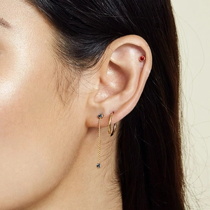 Close-up of gold tassel earrings with turquoise and red stones on a model's ear