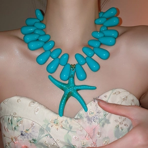 Detail der türkisfarbenen Perlenkette mit Seestern-Anhänger am Hals des Models