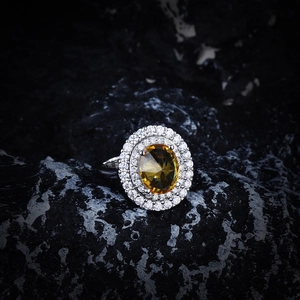 Detailed macro shot of an oval yellow gemstone ring with a double halo of white zircons