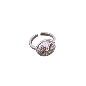 Bague ouverte argentée minimaliste avec une surface texturée ronde sur fond blanc pur