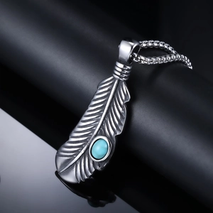 Detailed view of punk feather pendant with turquoise stone on polished black surface