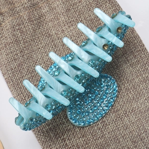 Detail of blue acrylic hair claw clip with sparkling rhinestones on a burlap bag