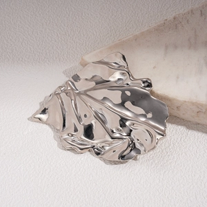 Macro view of metallic irregular pleated leaf brooch with glossy textured finish