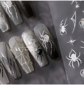 Detalle de pegatinas de uñas góticas 3D con patrones plateados de arañas y rosas