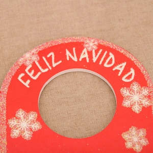 Close-up of red Christmas door hanger with glitter Feliz Navidad text on burlap