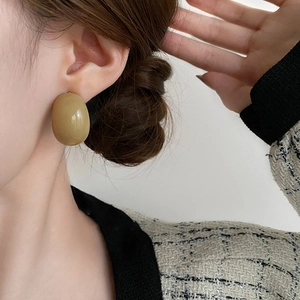 Élégantes boucles d'oreilles ovales en résine vert olive portées par un mannequin