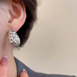 Macro shot of silver textured waterdrop earrings featuring unique hammered surface on ear