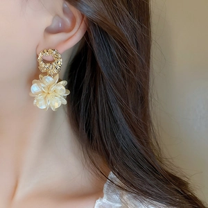 Gros plan d'un mannequin portant une boucle d'oreille fleur en acrylique et métal doré