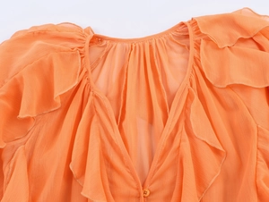 Detailed view of bright orange ruffled chiffon blouse with V-neck and layered textures