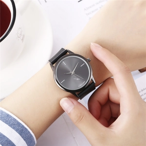 Detail of minimalist quartz watch with dark grey mesh strap on a clean lifestyle background