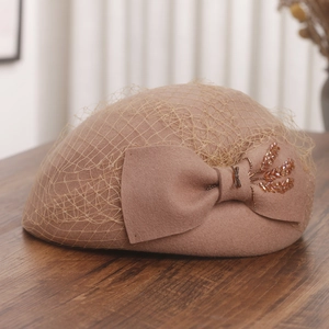 Detail of elegant wool beret featuring delicate mesh veil and beaded bow ornament