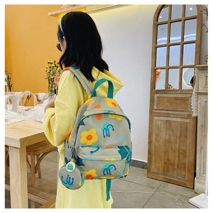 Detail of grey floral kids backpack featuring a matching round coin purse attachment