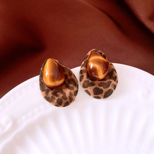 Detail of teardrop leopard print earrings with amber resin stone on ceramic plate