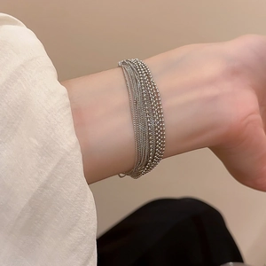 Detail of silver multi-layer layered chain bracelet with beaded links on model wrist