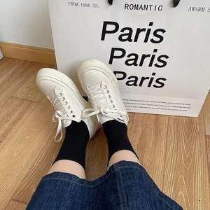 Klassische weiße Plateau-Sneaker aus Canvas mit Schnürung auf hellem Holzboden