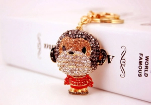 Close-up of sparkling rhinestone monkey keychain with golden ring on a white book