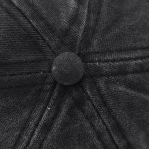 Dettaglio macro della corona del cappello in velluto a coste nero con cuciture e bottone