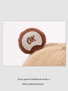 Detail view of beige corduroy kids hat featuring round ear decor and OK embroidery