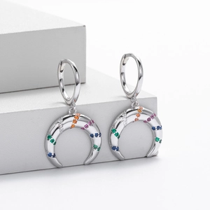Macro detail of S925 silver hoop earrings with crescent moon multi-color zircon charms