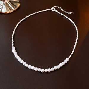 Vue détaillée du collier avec perles blanches et billes argentées sur fond sombre