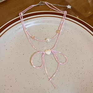 Detailed view of pink beaded necklace featuring a bow shape with heart and star accents