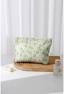 Detailed view of green floral jacquard fabric and brand label on a makeup bag