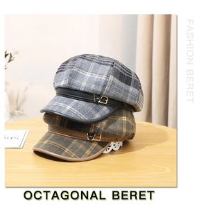 Detail of grey and brown plaid octagonal beret hats with leather straps and gold buckles