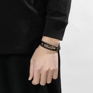 Close-up of men's multi-layer braided black leather bracelet with a gold magnetic clasp