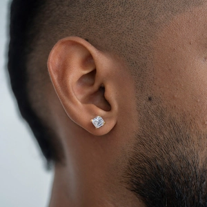 Close-up of a square-cut moissanite stud earring with gold four-prong setting on male ear
