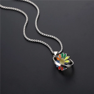 Rainbow daisy spinning pendant necklace with silver chain on black textured surface