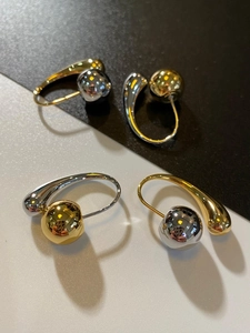 Detail of two-tone metallic teardrop ball earrings with polished gold and silver finish