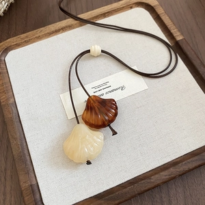 Close-up of vintage shell pendants with wooden beads on a woven rope sweater necklace