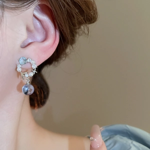 Gros plan de boucles d'oreilles fleurs bleues avec perles et cristal sur un modèle