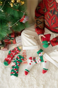 Christmas coral fleece socks with snowman and reindeer patterns on a plush white carpet