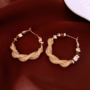 Créoles dorées en maille torsadée au design spirale vintage sur fond de soie élégant