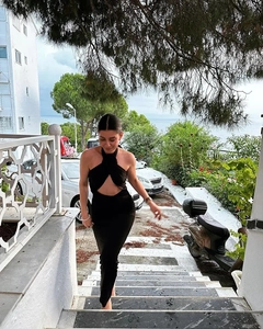Outdoor lifestyle shot of a black halter neck dress with front cutout and backless detail