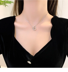 Close-up of interlocking silver rings necklace worn on a black velvet V-neck top